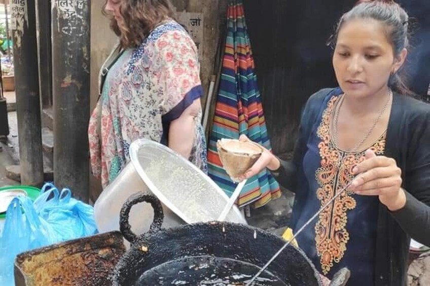 A person cooking outdoors, using a large pot and a strainer. 5