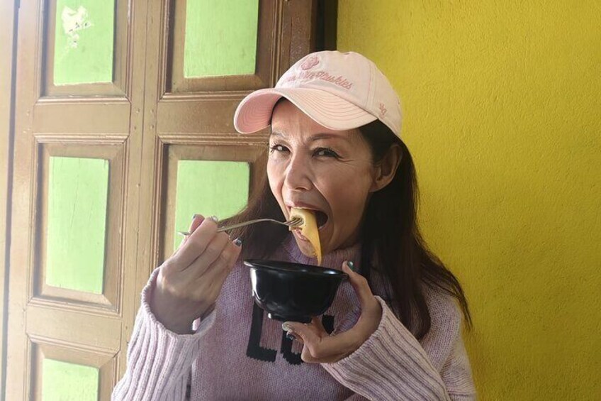 Una persona con gorra rosa y suéter, sosteniendo un plato y una cuchara, comiendo. 5