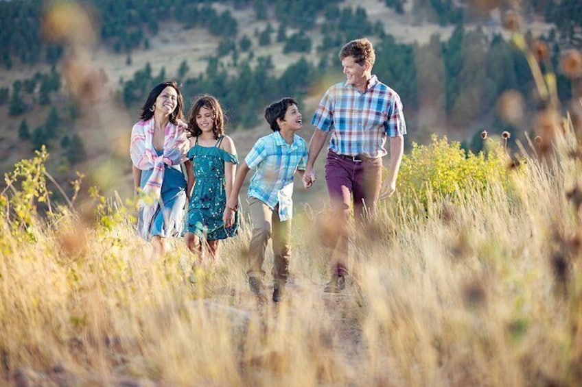 A family walking in a grassy field with a hilly landscape in the background. 1