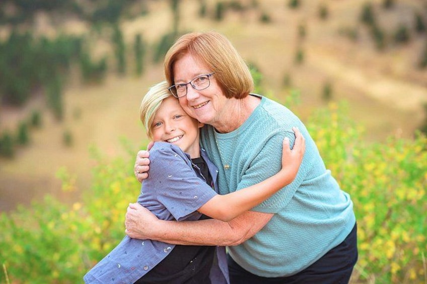 A person embracing another in a natural outdoor setting with greenery and hills in the background. 4