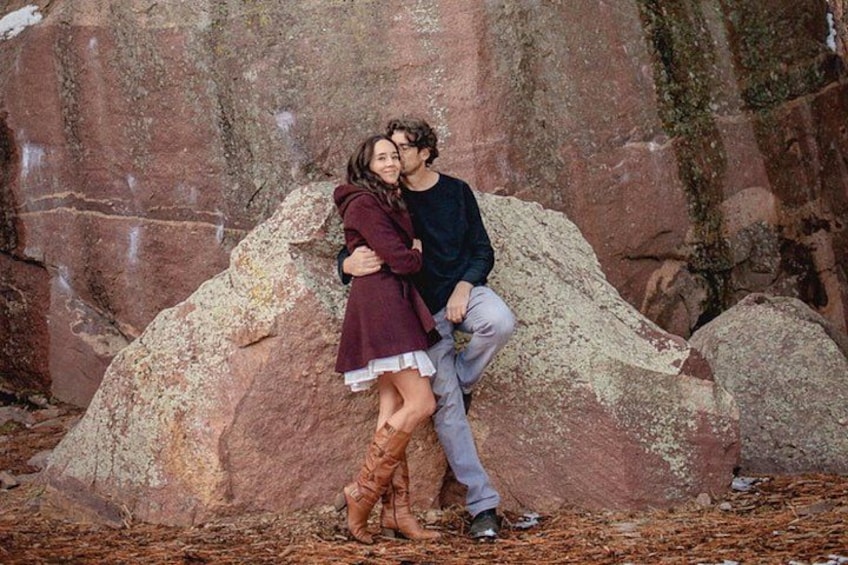 A couple embracing in front of a large rock formation. 5
