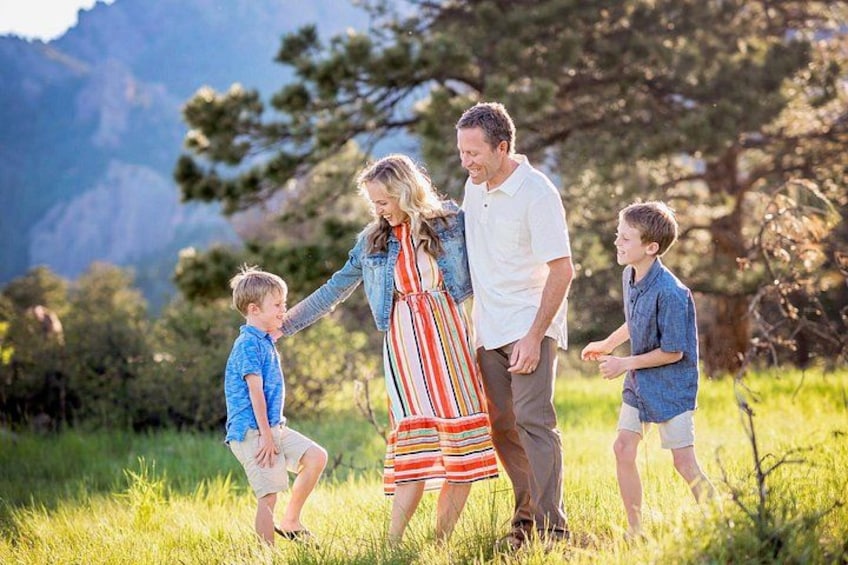 A family of four in a grassy field with mountains in the background. 2