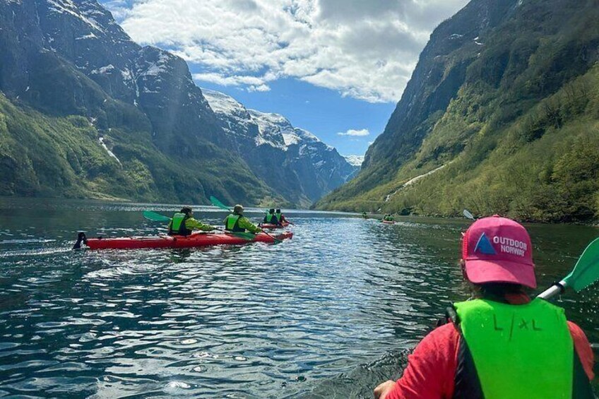 A group kayaking on a calm lake with mountains in the background. 2