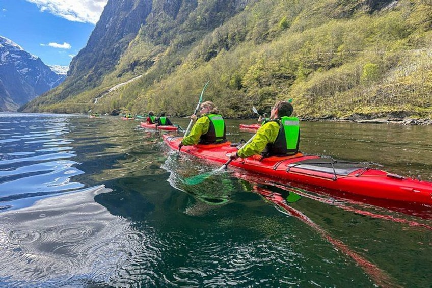 En gruppe mennesker kajakker på en rolig flod omgivet af bjerge. 2