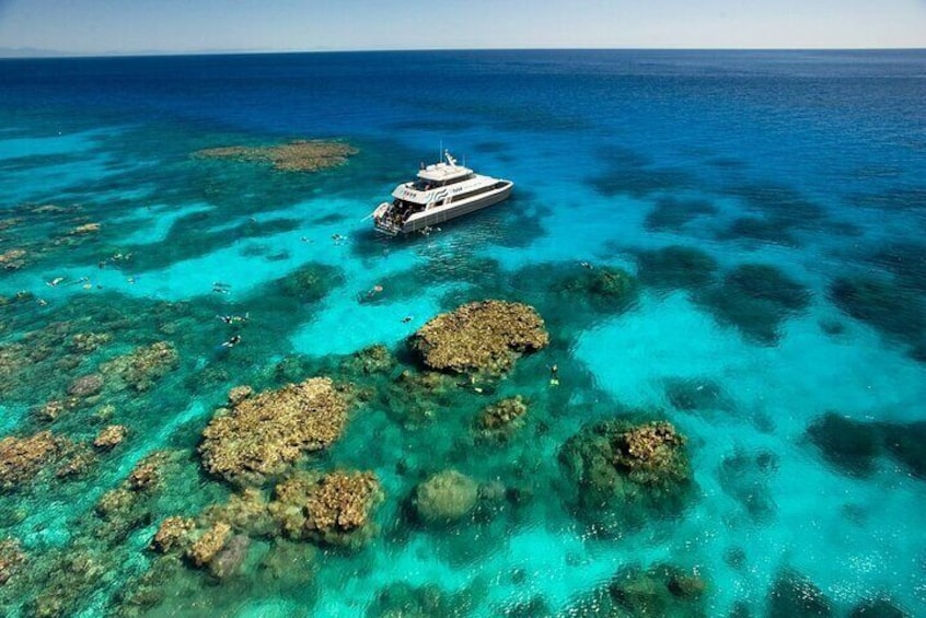 Een boot op helder turquoise water met zichtbare koraalformaties. 1