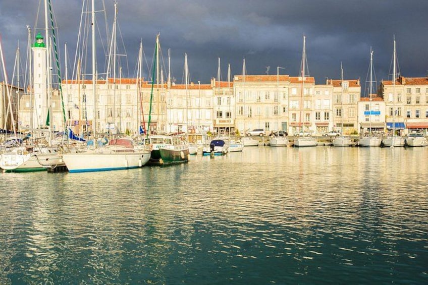 A harbor with boats docked along a waterfront with buildings in the background. 4