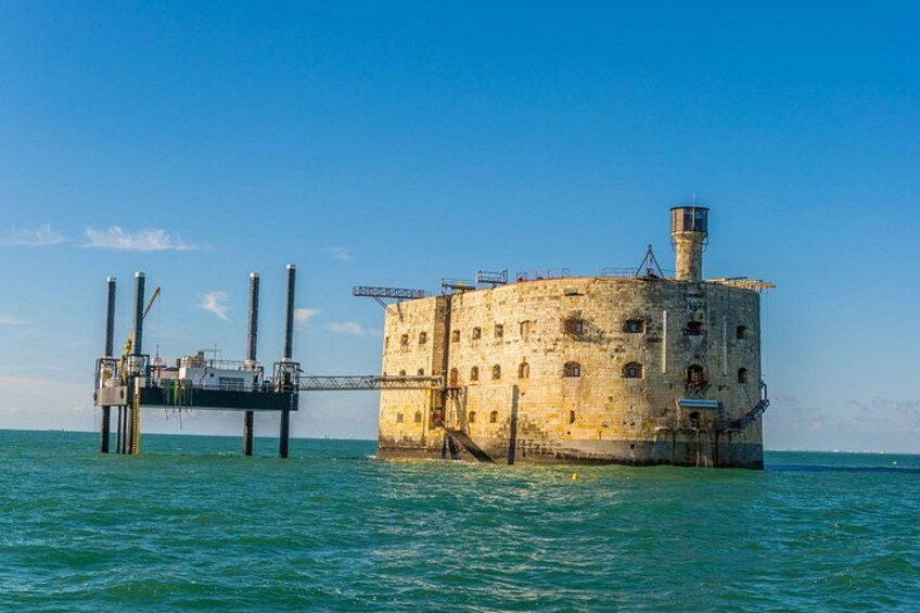 A historic stone structure with a lighthouse on a pier extending into the water. 2