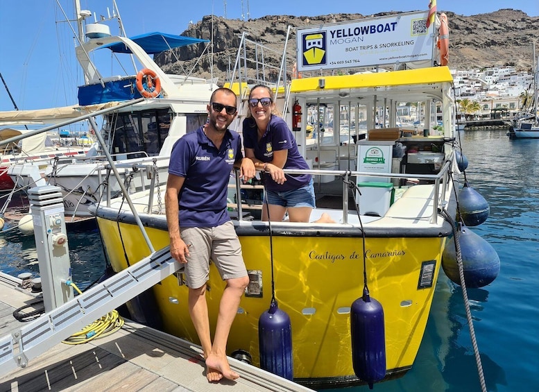A yellow boat named 'Yellowboat Mogan' docked at a marina with two people standing on the deck. 1