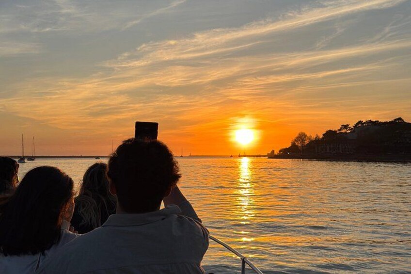 A sunset over a body of water with a boat and people on it. 4