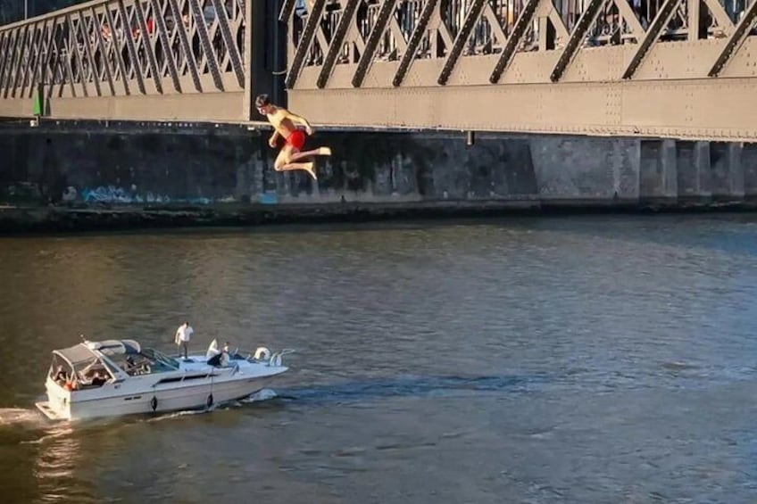 Iemand springt van een brug in het water, een boot op het water en de constructie van de brug. 2