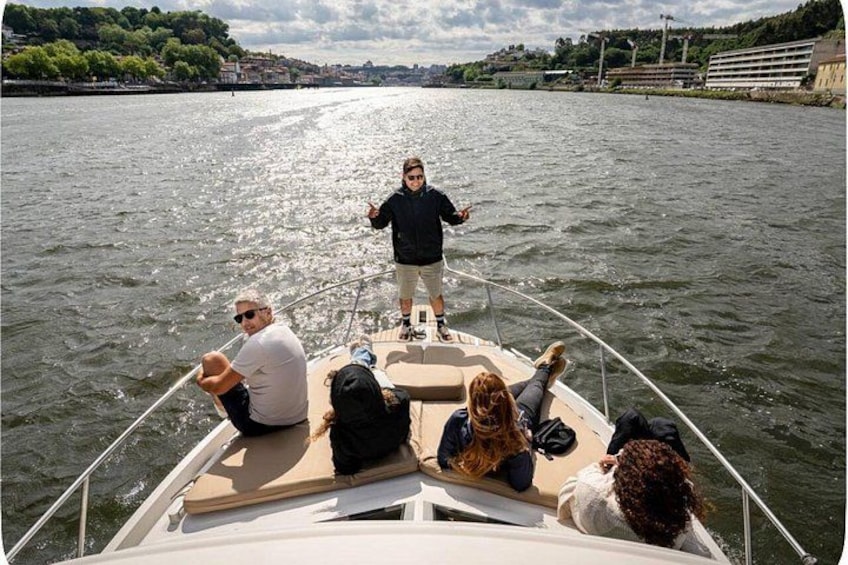 A boat with people on board, a river, and a distant shoreline with buildings. 3