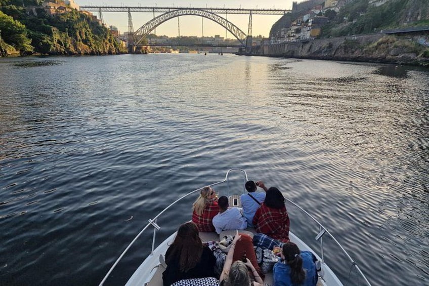 A group of people on a boat on a river with a bridge in the background. 1