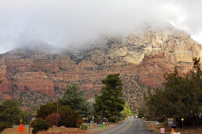 Une route qui mène à un paysage montagneux, avec des formations rocheuses rouges et une zone boisée. 3