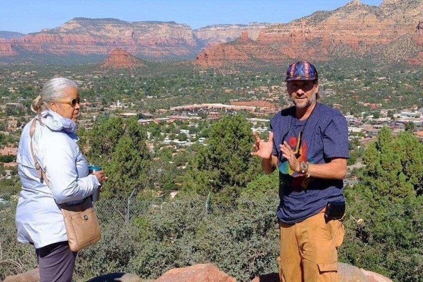 Deux personnes se tiennent debout sur un promontoire rocheux, avec un paysage montagneux en arrière-plan. 2