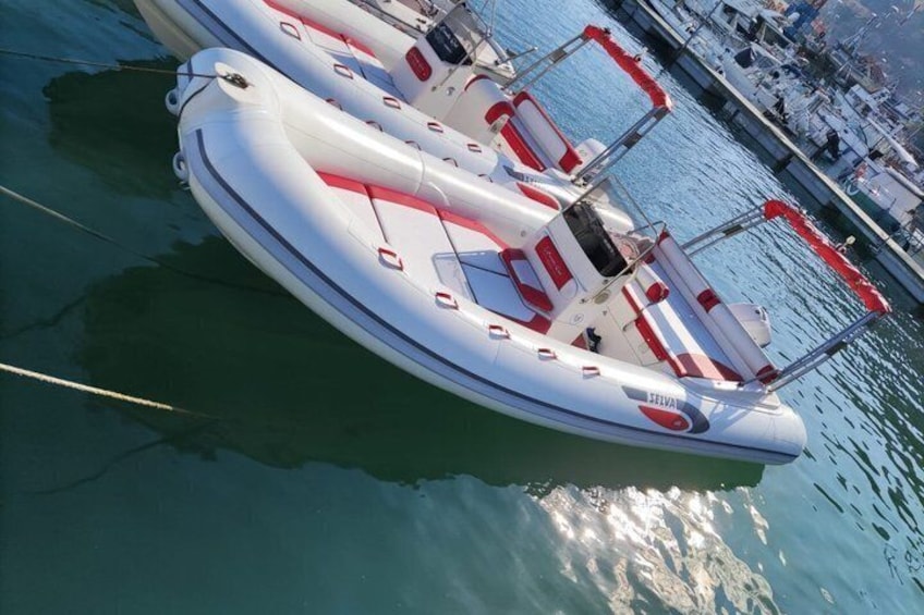 A white inflatable boat with red accents docked at a marina. 2