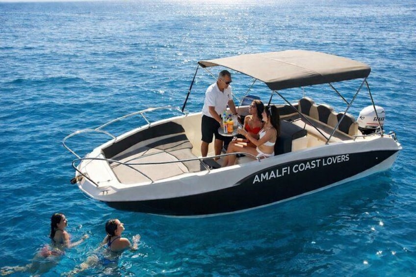A boat named 'AMALFI COAST LOVERS' on the water with people on board. 1