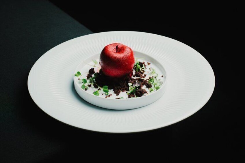 A red apple on a white plate with green garnish. 2