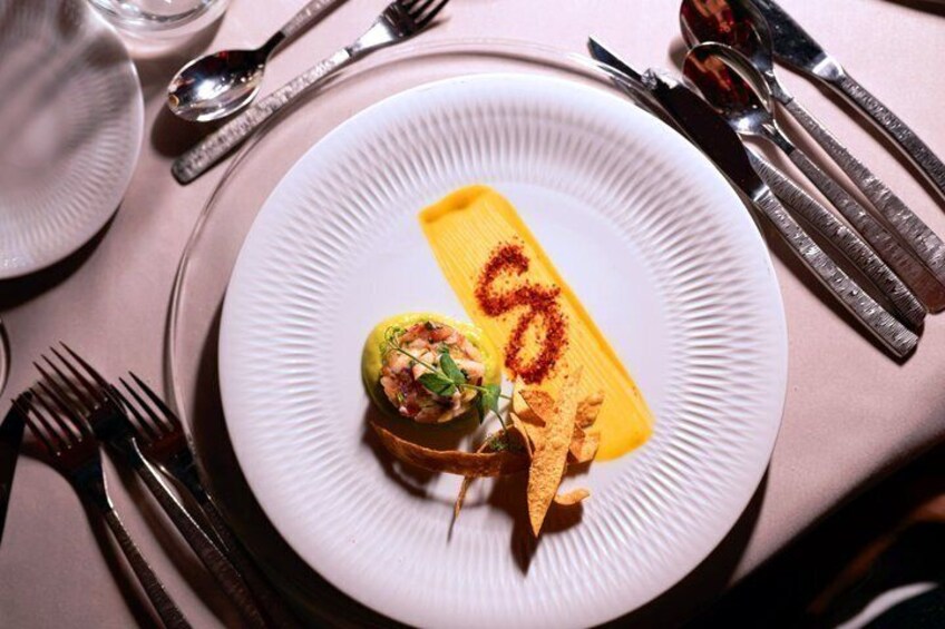 A white plate with a yellow dessert and a small green garnish. 3