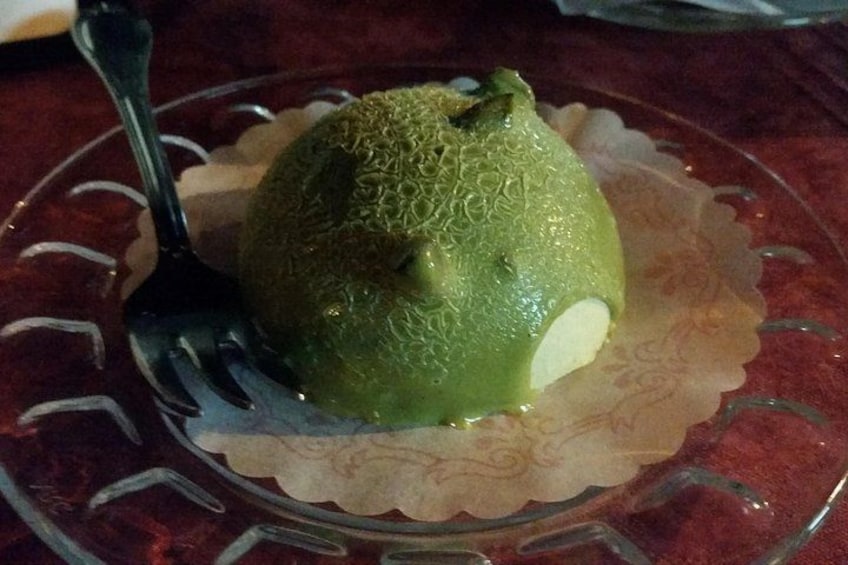 A green fruit on a glass plate with a fork. 2