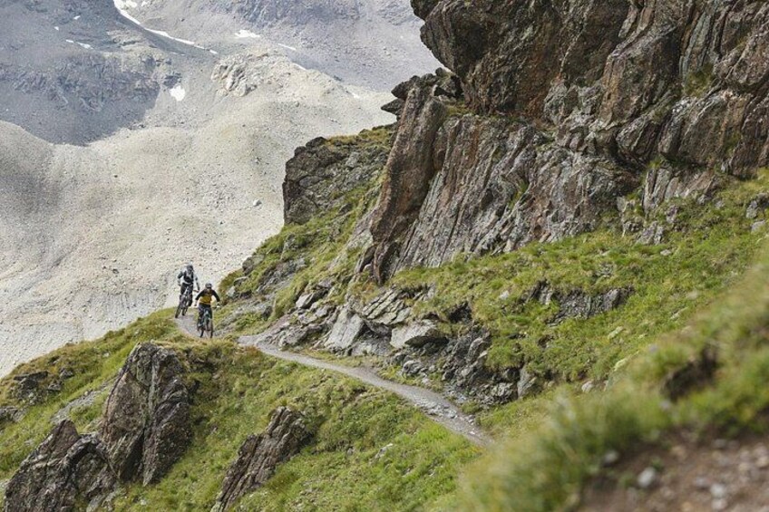 Un percorso di mountain bike con terreno roccioso e vegetazione rada. 2