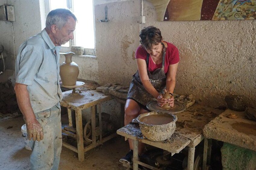 A pottery workshop with two people working on pottery wheels. 3