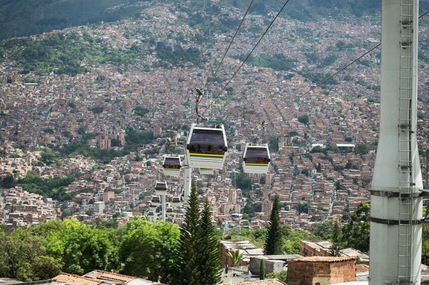 A cable car system with multiple gondolas, a cityscape in the background, and a prominent tower. 2
