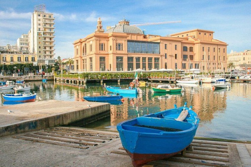 Un port de plaisance avec des bateaux, un grand bâtiment surmonté d’un dôme, et une vue sur la ville en arrière-plan. 4