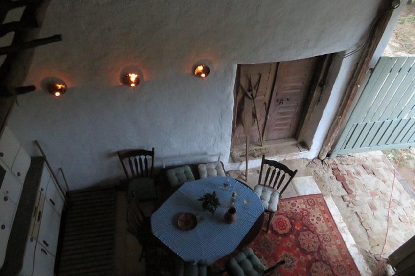 Un espacio exterior cubierto para comer, con una mesa, sillas, un tapete estampado y una puerta de madera. 3