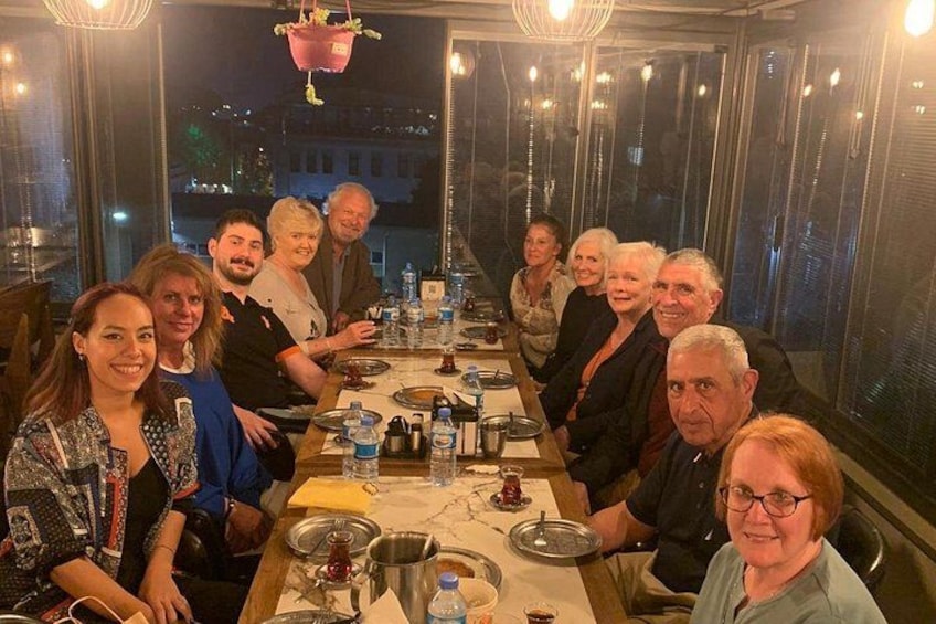 Un grupo de personas sentadas alrededor de una mesa en un restaurante con vista a la ciudad. 3