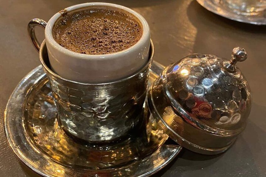 Una taza de café con un platillo y una tapa plateada decorativa. 5