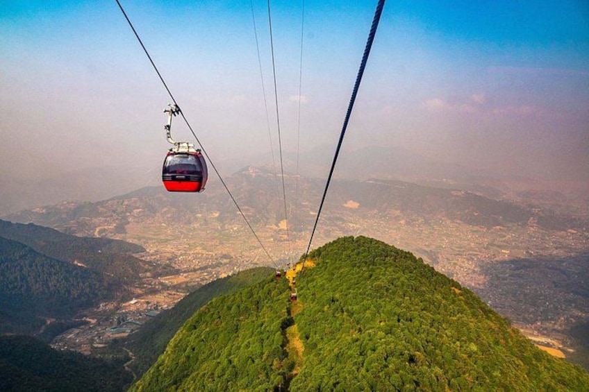 A cable car ascending a mountain with a view of a valley below. 1