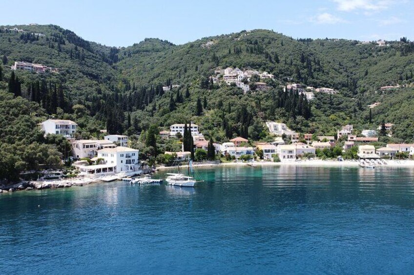 A coastal town with buildings along the shoreline, a boat docked near the water, and hills in the background. 2