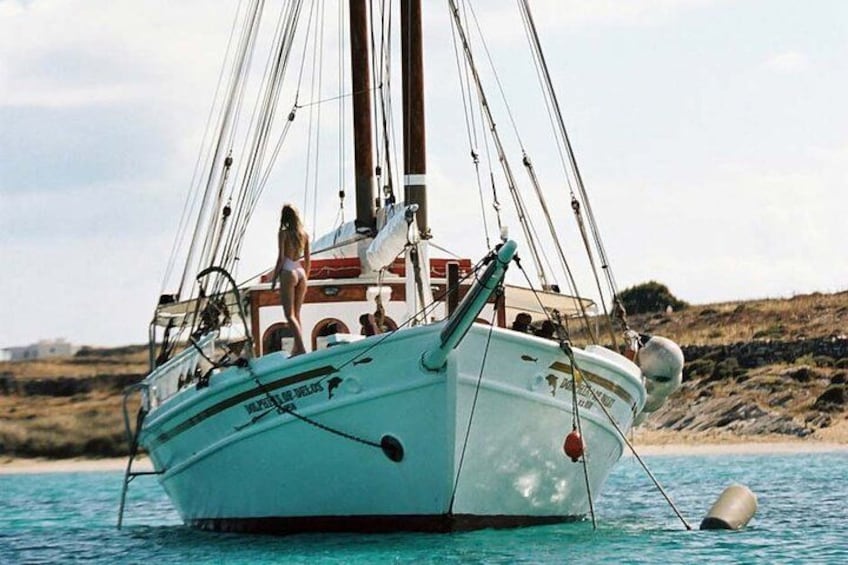 A sailboat on calm water with a person standing at the stern. 3