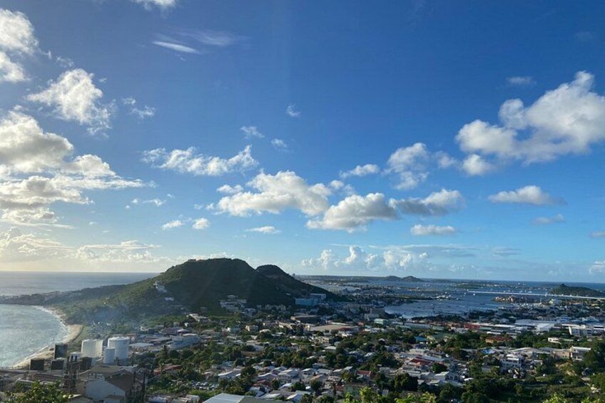 Un paysage urbain côtier avec une colline imposante, une plage et un ciel dégagé. 1
