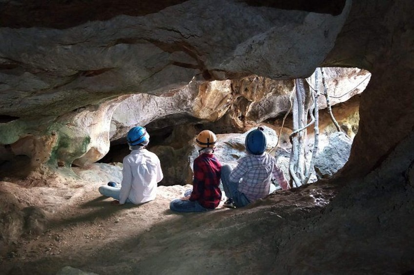 Tre personer sitter inne i en grotta. 2