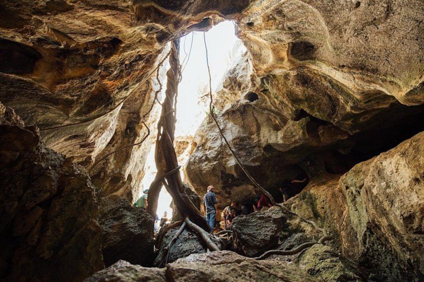 En grotta med stalaktiter och stalagmiter, en hängbro och människor som utforskar området. 1