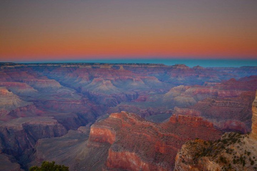 Un extenso paisaje de cañón con formaciones rocosas estratificadas y un cielo al atardecer. 1