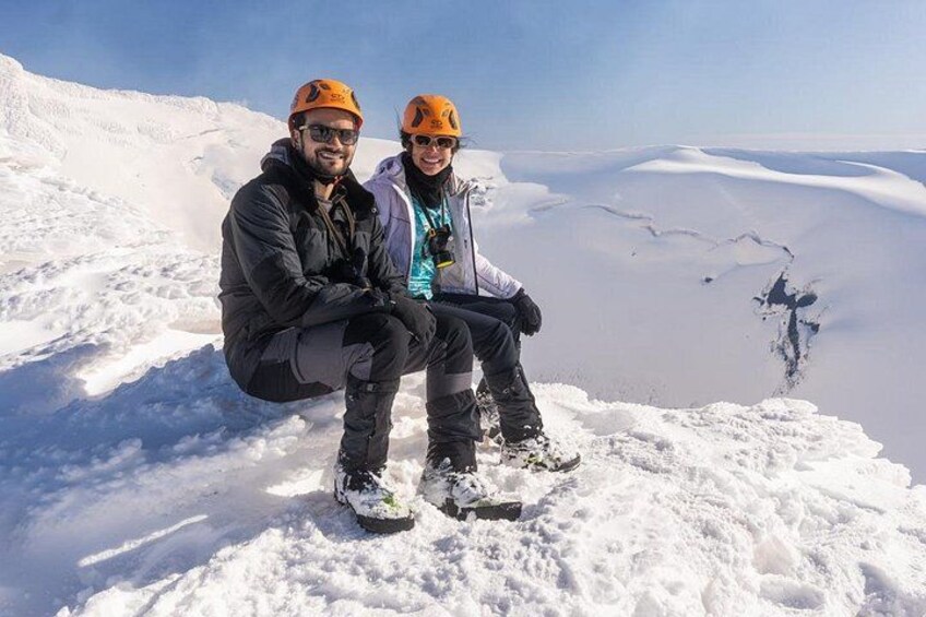 Two people sitting on a snowy mountain peak with a vast snow-covered landscape in the background. 4