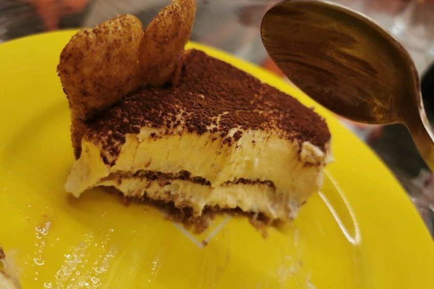 Una fetta di tiramisù su un piatto giallo con un cucchiaio. 5