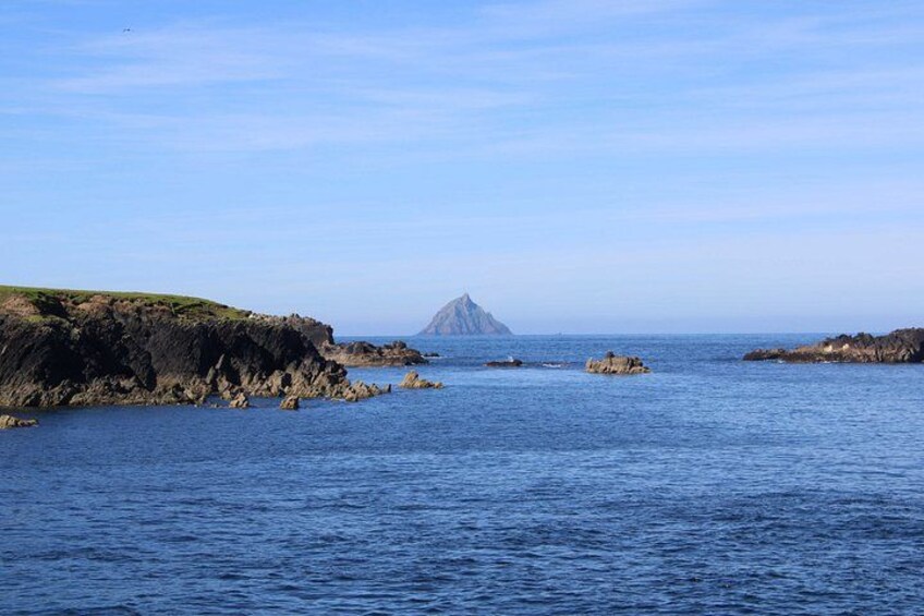 A coastal landscape with rocky outcrops and calm blue waters. 2