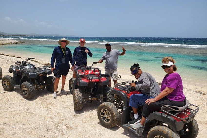 A group of people on a beach with ATVs. 1