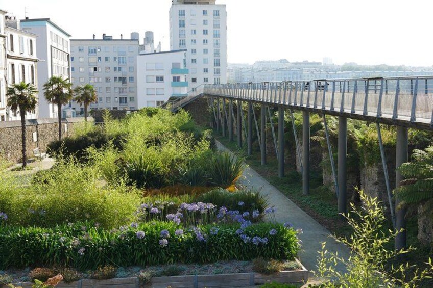 A pedestrian bridge over a garden with various plants and flowers. 2