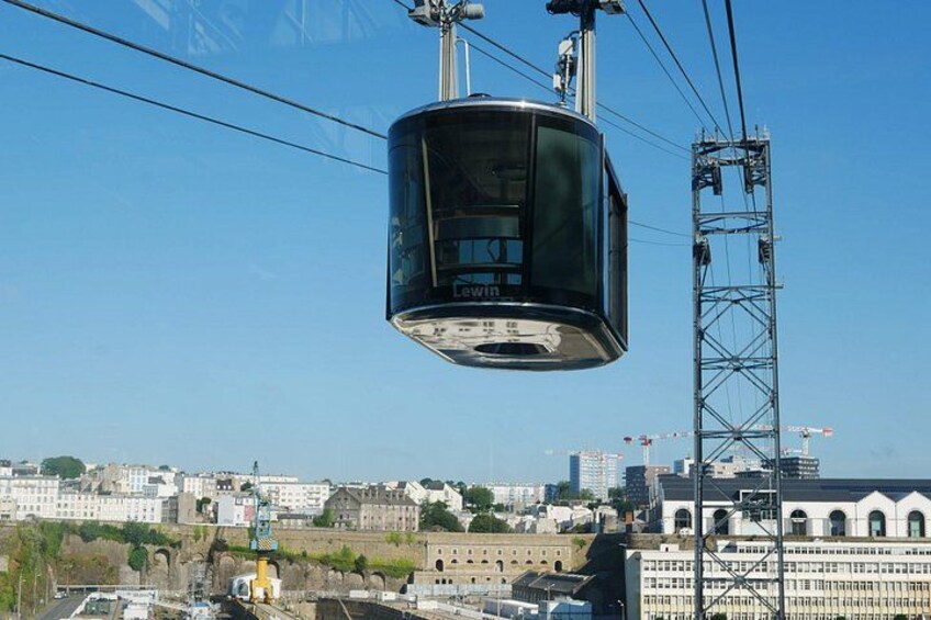 A cable car suspended above a cityscape with historical buildings and construction cranes in the background. 2
