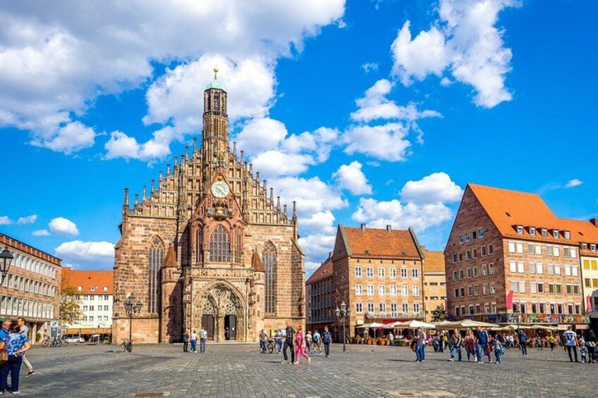 A historic church with a tall spire, a cobblestone square, and traditional buildings. 3