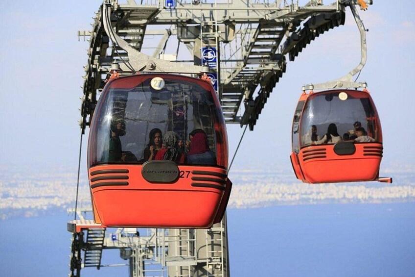 Two red cable cars suspended by cables, with a cityscape in the background. 4