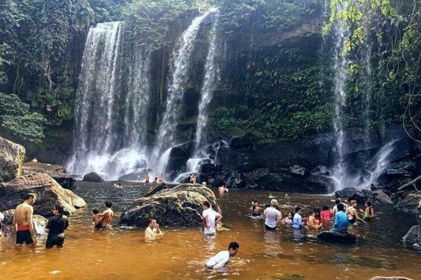 A waterfall with people bathing in the water. 1
