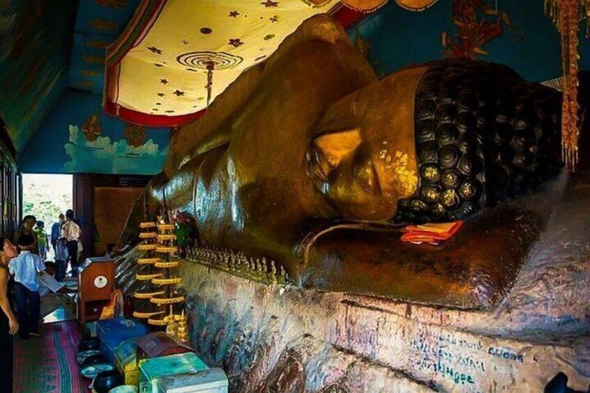 A large golden statue of a seated figure, possibly a Buddha, with a backdrop of colorful murals and a staircase leading up to it. 4