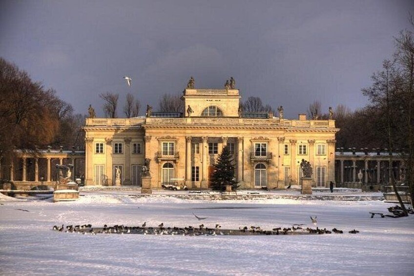A large classical building with a symmetrical facade, surrounded by snow-covered ground and bare trees. 4