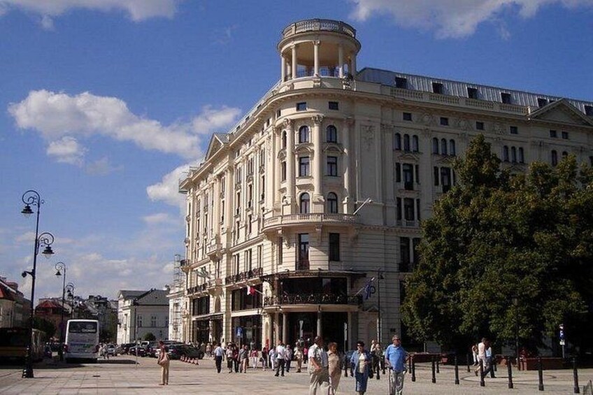 A historic building with classical architecture, a bustling square with pedestrians, and a clear blue sky. 5