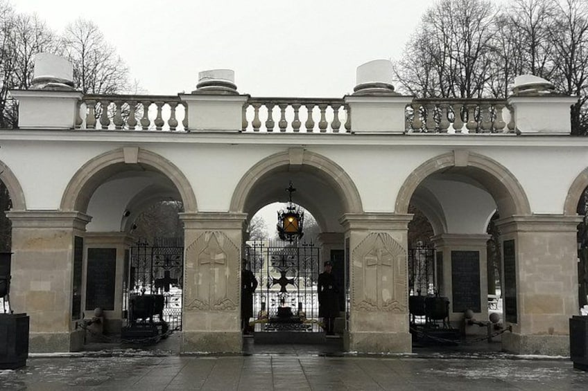 A historic building with three large arches, a gated entrance, and a decorative balustrade. 3